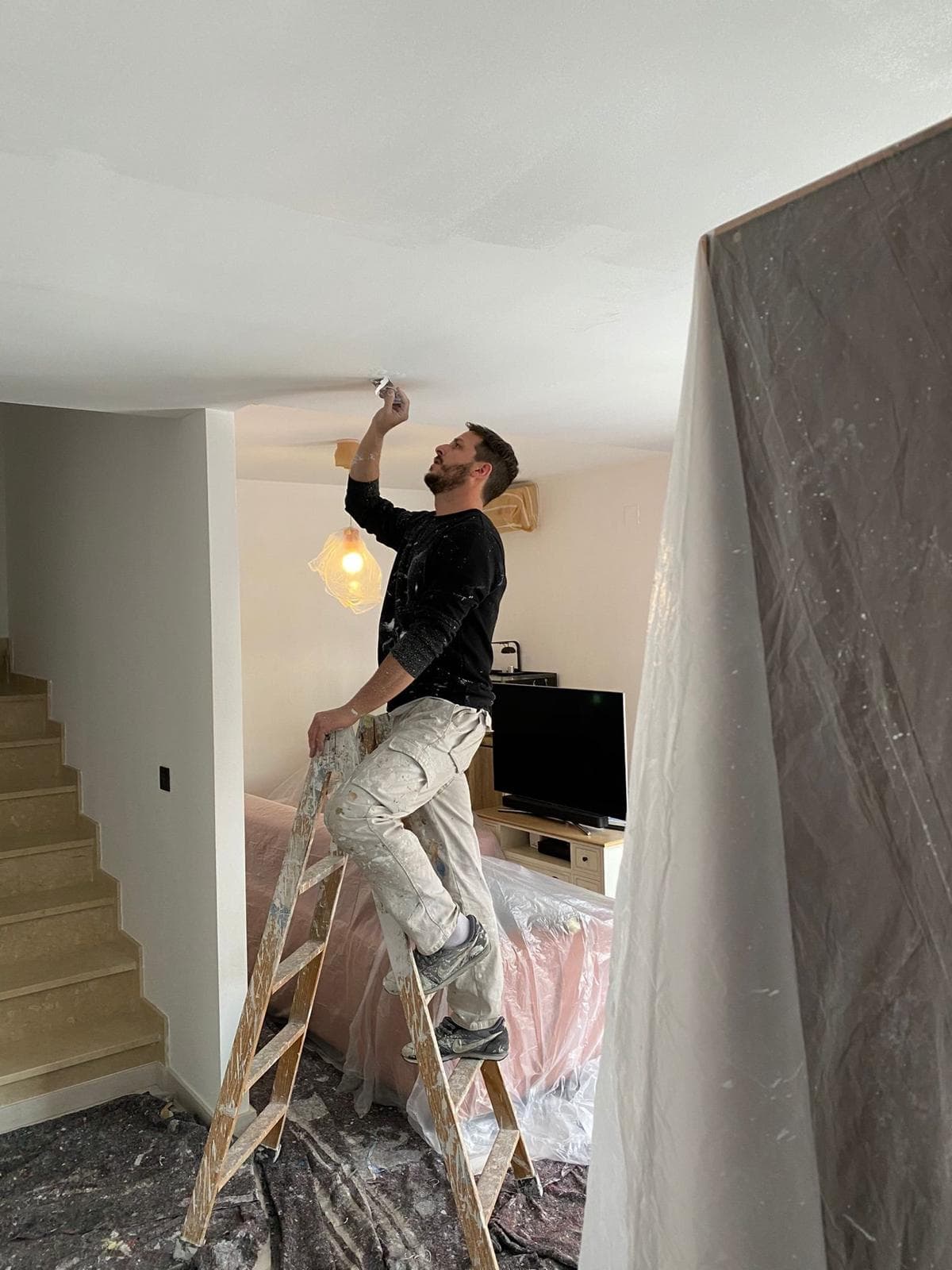 Emilio pintando el techo de una vivienda